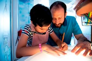 A dad helps his daughter with her homework.