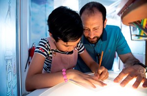 A dad helps his daughter with her homework. 