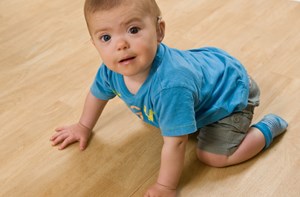 A baby crawling with a toy in his hand