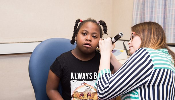 An audiologist uses an otoscope to look into a child's ear.