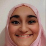 Photo of a young woman wearing a pink headscarf smiling at the camera