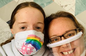 Photo of a mum and daughter, wearing a cloth face mask and a clear plastic face mask