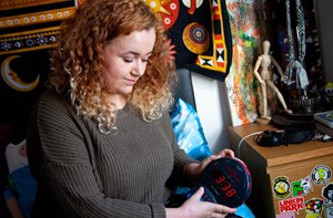 A young woman with curly hair presses a button on a Sonic Boom alarm clock.