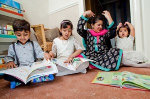 A mother and her three children, reading sign language books.