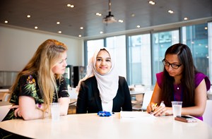 Three women sit at a table in an office.