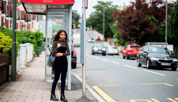 A teenager waits at a bus stop.