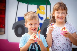 A deaf young boy and a girl eating ice cream on holiday