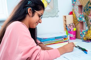 A deaf girl with a cochlear implant studying at desk