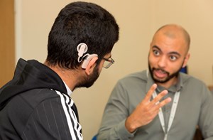 A man signing to a deaf boy with a cochlear implant