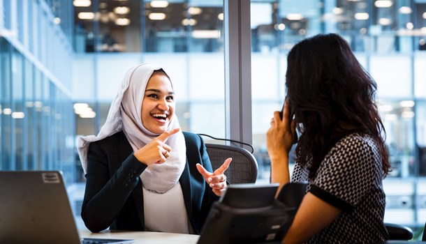 A woman with a headscarf signing to an interpreter on the phone in an office