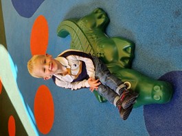 Boy sitting on crocodile toy