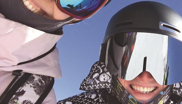 Two smiling boys in snowboarding helmets and sun goggles.