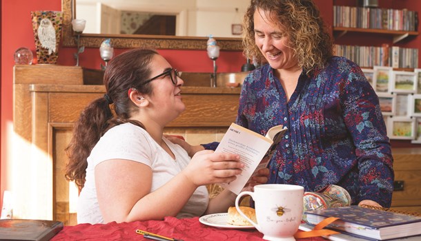 Young woman wearing a hearing aid showing a book to her mum