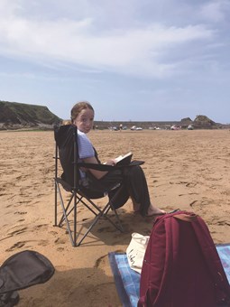 Girl reading on beach in chair