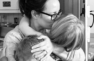 Mum kissing and holding her two young children