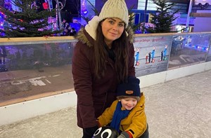 Mum and son ice skating using a penguin aid