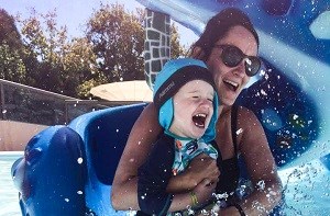 Mom and young son going down waterpark slide together