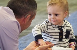 Deaf baby playing and smiling at man with hearing aid