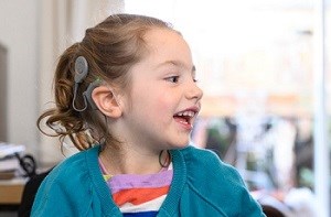 Olive (4) smiles wearing her cochlear implants