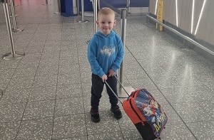 Kenzie (3) rolling his suitcase at airport check-in