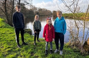 Charlotte (8) standing by a pond with her three older brothers