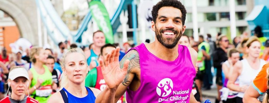 Smiling marathon runner wearing purple National Deaf Children's Society vest