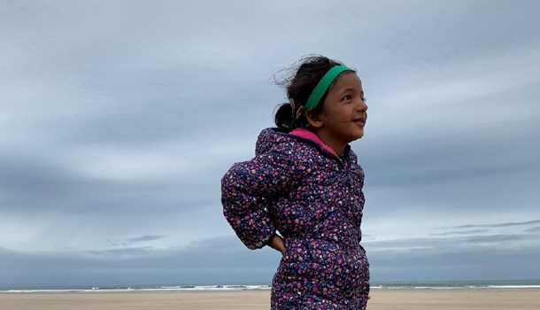 Jasmine standing on a beach wearing a cochlear implant band.
