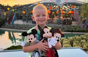 Kenzie (4) hugging two Mickey Mouse toys