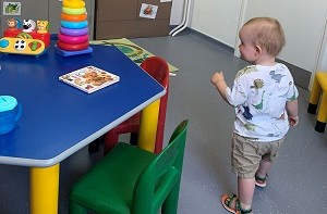 Freddie (1) walking around a colourful activity table