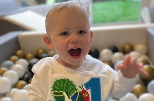 Jack (1) smiling in a ball play pit