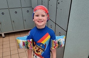 Kenzie (4) in a swimming pool locker room with cap and swimsuit on