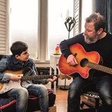 Moji (13) and his dad sat playing guitars in front of a window.