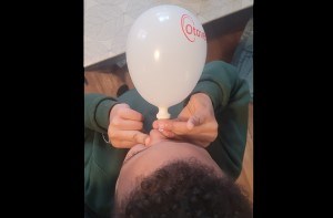 Isaac (6) blowing into an Otovent balloon
