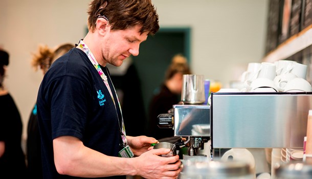 A deaf young man wearing cochlear implants working as a barista in a cafe.