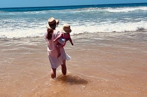 Mum Yasmin holds her toddler Olivia on a beach in Portugal