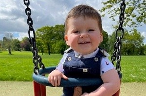 George (1) sitting in a baby swing at the park