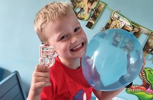 Kenzie (5) holding a balloon and candle in the shape of a 5