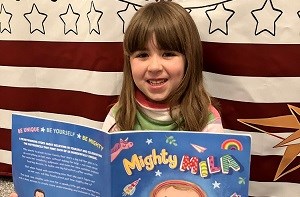Isabelle (5) holding a book titled 'Mighty Mila'