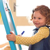 Young girl drawing on a whiteboard easel