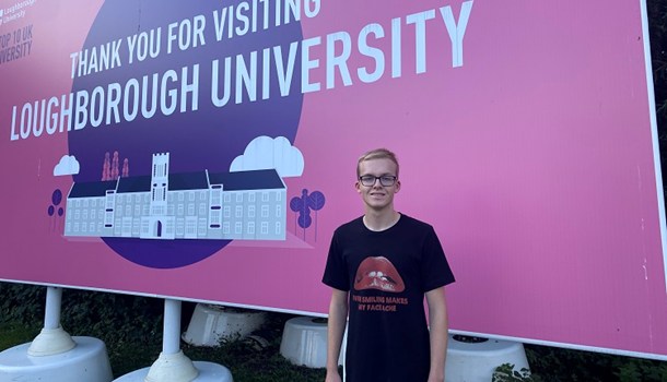 Daniel (18) standing in front of a sign for Loughborough University