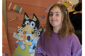 Chloe (10) stands in front of a Bluey cartoon poster