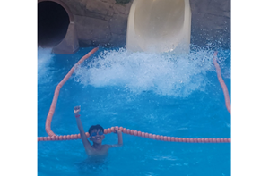 Isaac (9) in a swimming pool near the bottom of a slide.