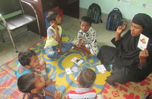 A teacher and five small children sat in a circle on the floor