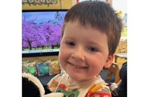 Young boy holding a stuffed animal in a nursery setting